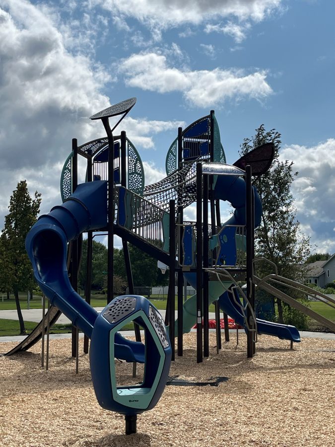 Blue and teal multi-level playground with tube slide, rope climber and Nido Spinner.
