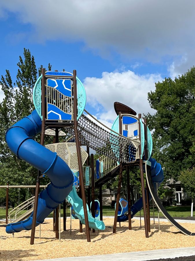 Blue and teal multi-level playground with tube slide and rope bridge 