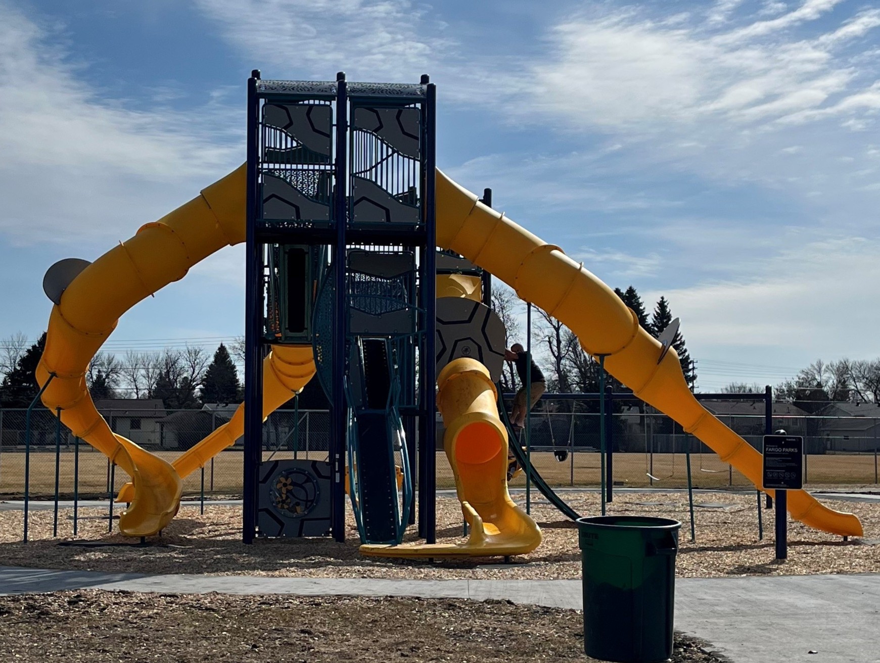 Multi-level navy and grey colored play structure with 4 yellow enclosed slides.